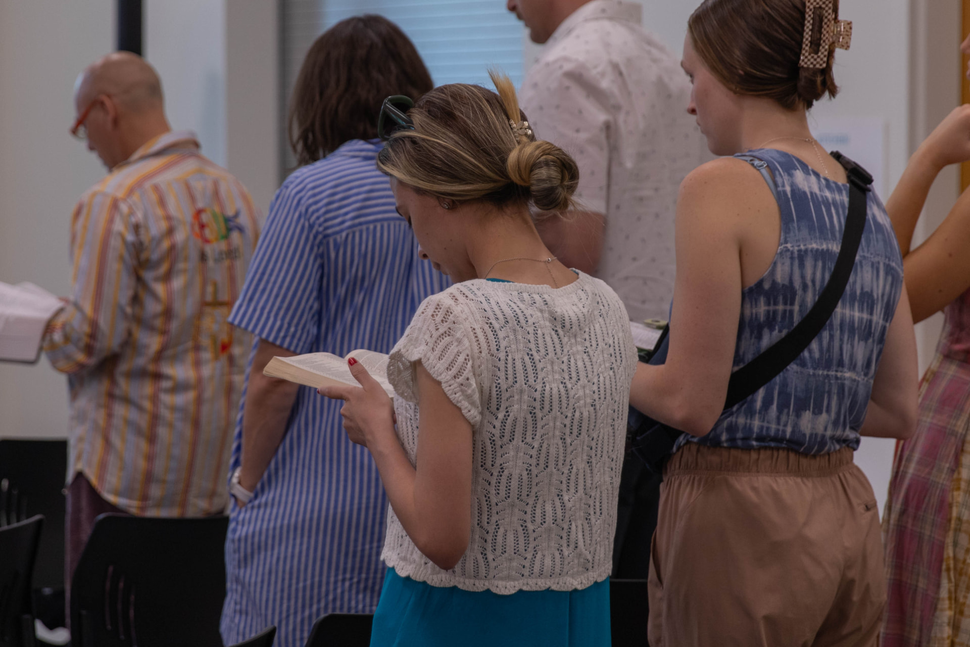 People standing and reading from open Bibles during the service